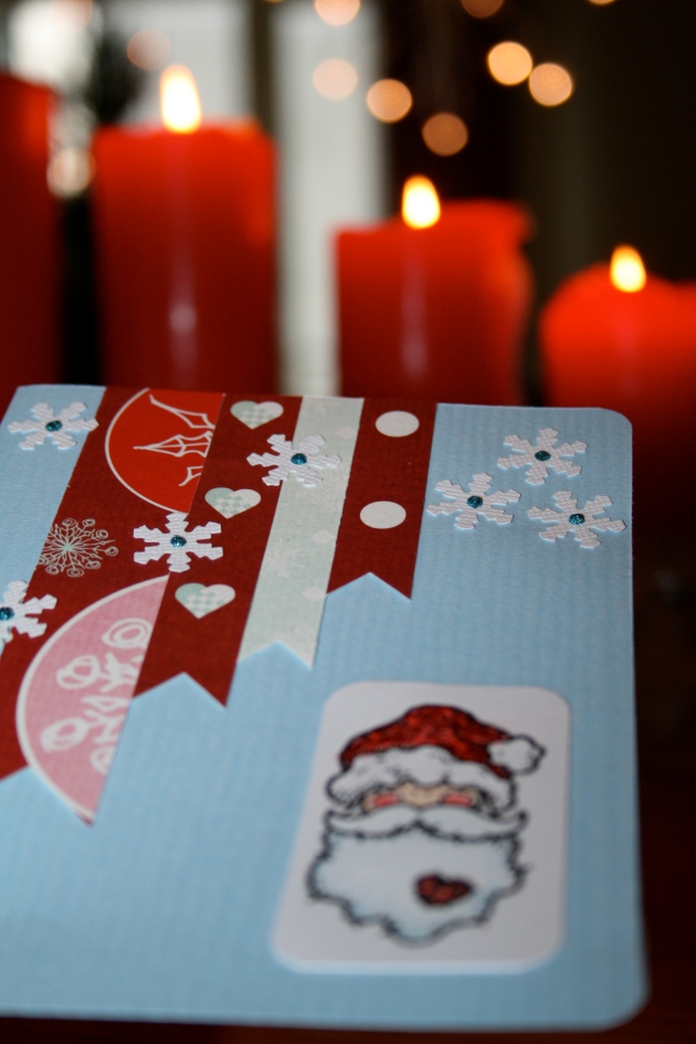 Julkort 2013 - ljusblått kort med pappersremsor och snöflingor och tomte (närbild på snöflingorna)